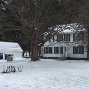 two story farmhouse and gazebo stand in winter