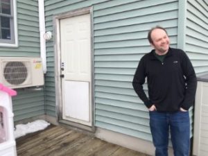 Mr. kimball outside of the home with the air source heat pump